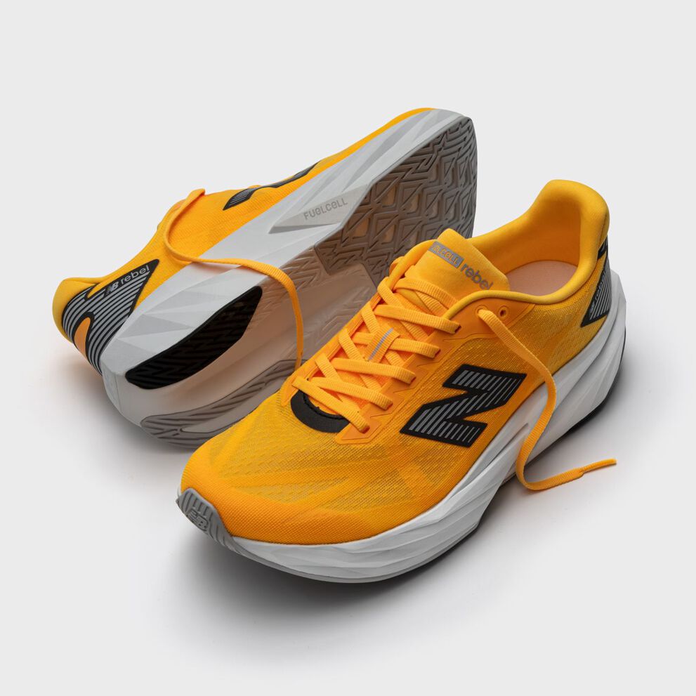 A pair of orange FuelCell Rebel shoes on a grey background.